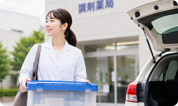 薬局前で訪問用ケースを持つ薬剤師